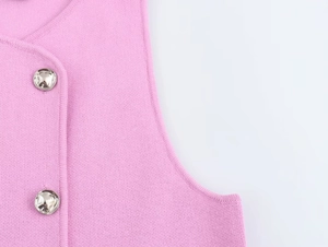 Dettaglio gilet in maglia rosa con bottoni argentati testurizzati e trama fine