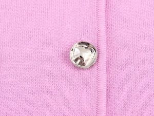 Dettaglio ravvicinato di gilet in maglia rosa con bottone metallico argento irregolare