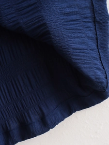 Detailansicht der dunkelblauen Smocking-Stoffstruktur und feiner Nähte am Sommeroutfit