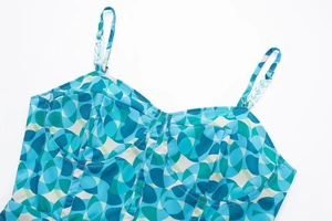 Détail de la mini robe imprimée géométrique bleu et vert avec bretelles chaîne