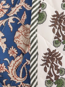 Macro shot of quilted fabric detailing vintage floral print and decorative twill edging