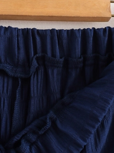 Detail des elastischen Faltenbunds an dunkelblauen Weitbeinhosen mit gerippter Textur