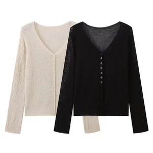 Detail of V-neck knit cardigans in beige and black with ribbed texture and small buttons