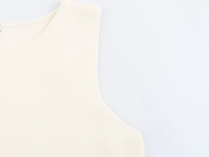 Dettaglio di un gilet in maglia bianco panna con focus su scollatura e tessitura
