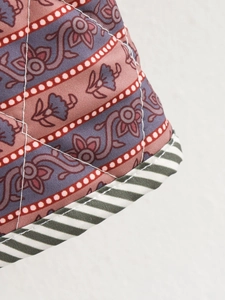 Macro detail of diamond quilted jacket fabric with floral print and striped trim edge
