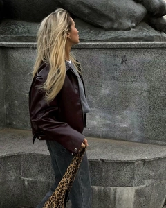 Detail of burgundy leather biker jacket featuring a notched lapel and silver metal buckles