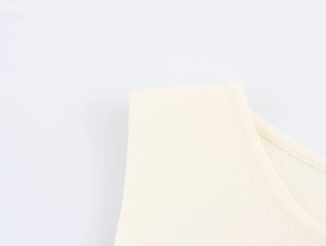 Dettaglio ravvicinato della trama a costine e dello scollo su un gilet in maglia beige