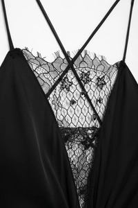 Détail de robe en satin noir avec décolleté en V, dentelle florale et paillettes