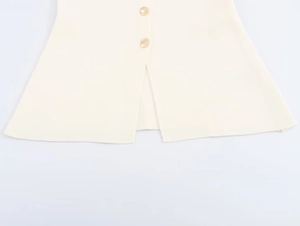Dettaglio ravvicinato del gilet in maglia crema con trama a coste e bottoni dorati