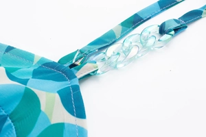 Détail de la bretelle de robe à fleurs avec maillons en acrylique et coutures fines
