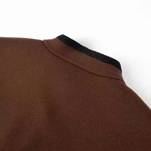 Close-up of wool jacket featuring dark brown fabric and black ribbed knit collar