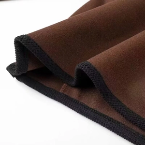 Detailed view of brown faux suede fabric with decorative black braided edge stitching
