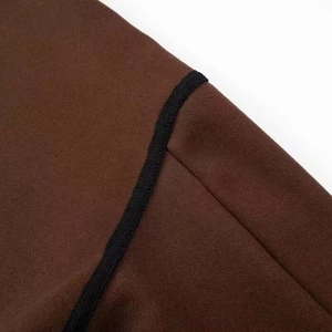 Detail view of brown wool fabric with high-quality black woven piping and stitching