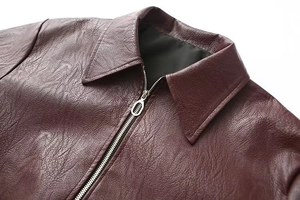 Detailed view of burgundy leather jacket featuring a classic lapel and silver metal zipper