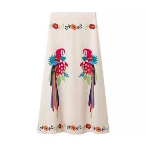 Detail of high-waist midi skirt featuring colorful parrot prints and floral embroidery