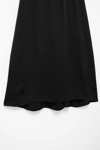 Détail de l'ourlet asymétrique élégant sur cette robe en dentelle noire au tissu fluide