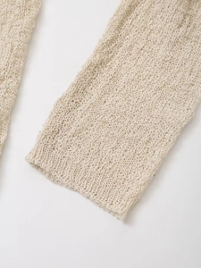 Detailed close-up of beige hollow knit texture and ribbed cuff on women's cardigan