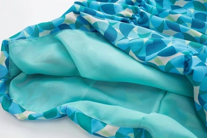 Détail de robe en mousseline à motifs géométriques sarcelle avec doublure et texture plissée