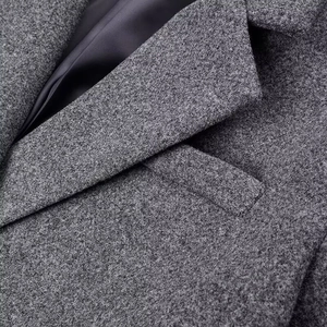 Detailed close-up of dark grey wool coat with notched lapel and premium inner lining