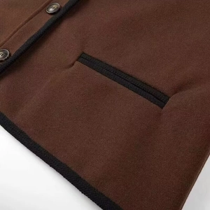 Close-up of brown wool coat featuring black woven trim and dark tortoise shell buttons