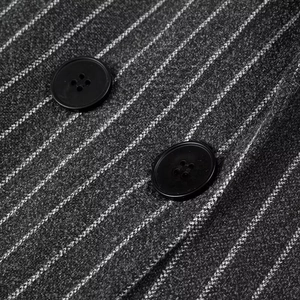 Close-up of grey pinstripe fabric texture with two matte black round buttons for a coat