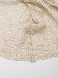 Close-up of cream knit fabric showing detailed mesh crochet texture and soft finish