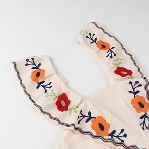 Detail of ruffled edge with floral print and multicolored embroidered wavy hemline