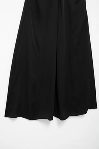 Gros plan détaillé de l'ourlet de la robe en satin noir avec plis élégants et raffinés