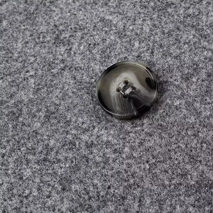Macro shot of marble-textured resin button on premium grey wool blend fabric coat