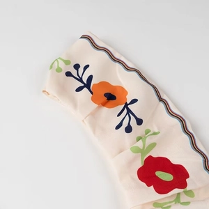 Detail of ruffle top with orange floral print and colorful striped edge texture