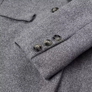 Detail of grey wool blend coat sleeve featuring three tortoiseshell pattern buttons