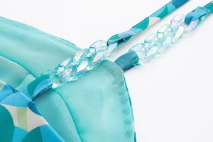 Détail de la robe turquoise avec des bretelles en chaîne de plastique irisé et imprimé