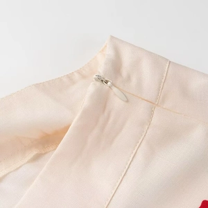Detail of invisible zipper closure on light beige ruffled skirt with smooth woven texture