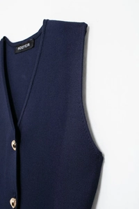 Close-up detail of golden spherical buttons on navy blue V-neck knitted vest