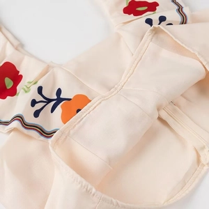 Detail of floral print fabric with rainbow stripe trim and hidden zipper on beige dress