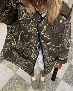 Detail of dark green quilted jacket featuring retro paisley floral print and blue trim