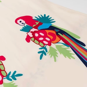 Detailed macro view of vibrant parrot print on cream fabric with ruffles