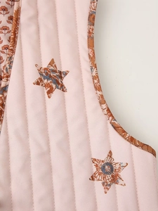 Detail der rosa gesteppten Weste mit Sternenmuster und brauner floraler Paspel