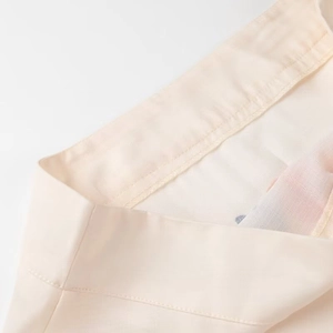 Macro detail of high-quality stitching and light beige woven fabric on a summer skirt set