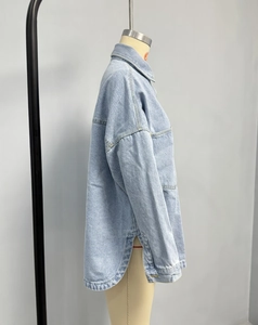 Detail view of light blue denim jacket featuring side slits and curved hemline