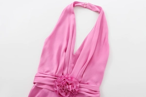 Détail de la robe midi en satin rose avec une fleur en tissu décorative à la taille