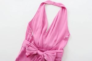 Détail d'une robe midi en satin rose avec un grand nœud à la taille et un col en V profond