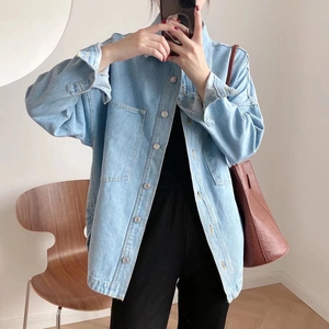 Detail of light blue denim jacket with silver buttons and front flap pockets