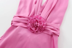 Gros plan sur une grande fleur 3D en tissu et plissage sur une robe midi satinée rose