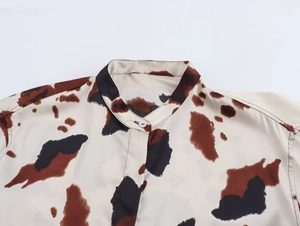 Detailed view of women's shirt featuring a band collar and a subtle animal cow print pattern