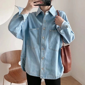 Detail of light blue oversized denim jacket featuring large chest pockets and metal buttons