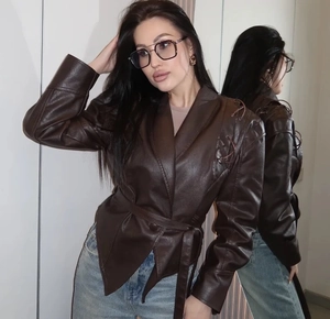 Détails d'une veste vintage en similicuir marron avec ceinture et épaulettes tressées