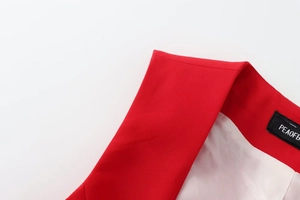 Dettaglio del colletto di un blazer rosso con texture pregiata ed etichetta interna