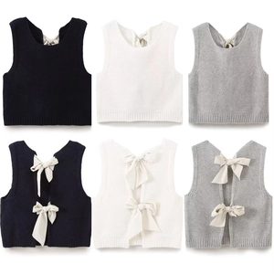 Dettaglio del gilet in maglia con schiena scoperta e fiocchi in nero, bianco e grigio