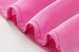 Détail de l'ourlet de la robe midi en satin rose vif avec des coutures fines et drapé doux